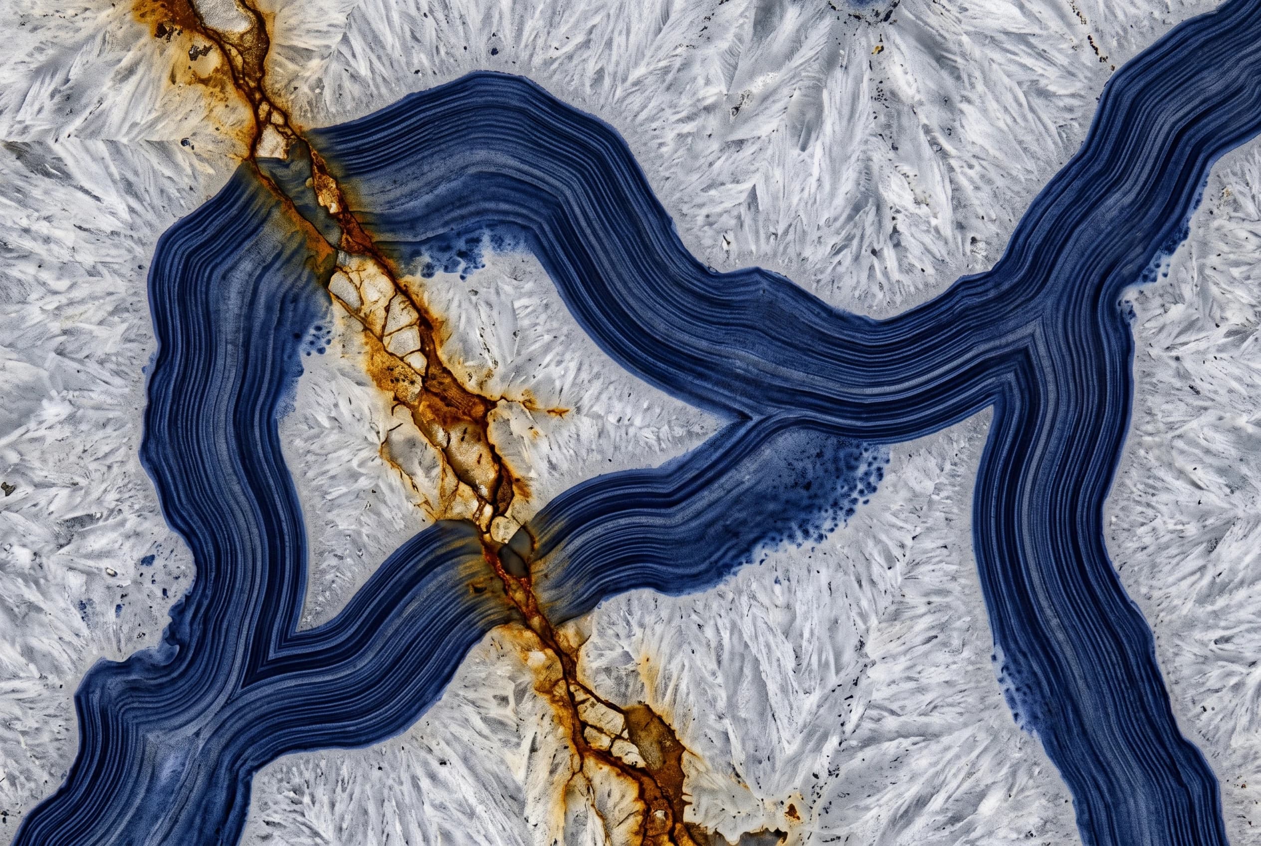 An agate thin section under the microscope: indigo bands crossed by an ochre vein