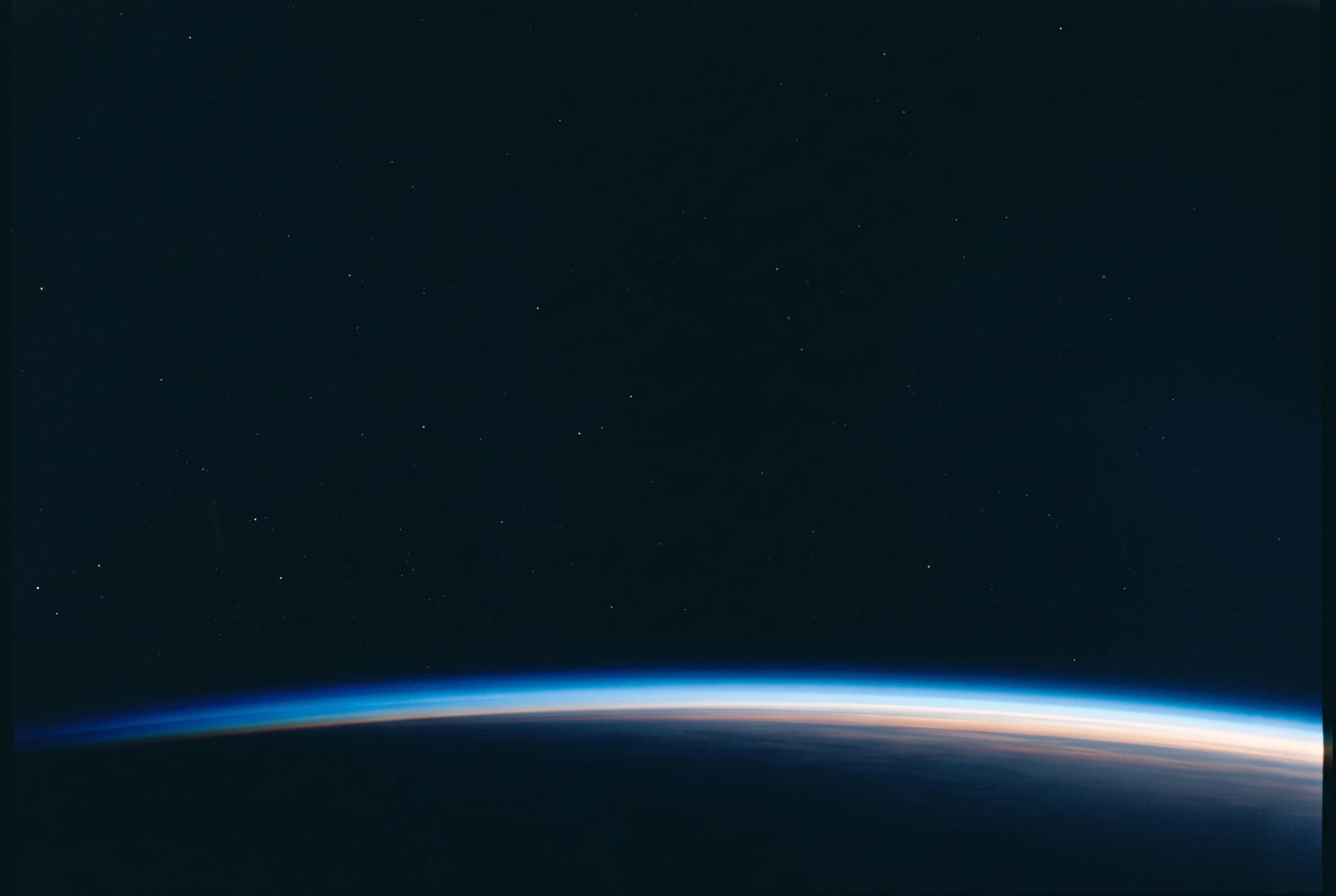 Earth's limb from orbit, a thin band of atmosphere under empty black space